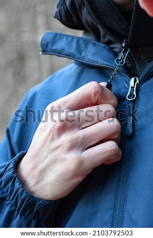 Close man hand holding jacket zipper
