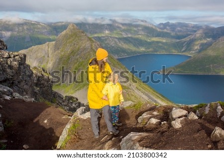 Happy family, standing on a rock and looking over Segla mountain on Senja island, North Norway. Amazing beautiful landscape and splendid nature in scandinavian country Royalty-Free Stock Photo #2103800342
