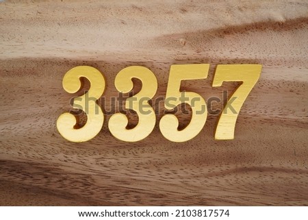 Golden Arabic numerals 3357 on a dark brown to white wood grain background.