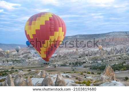 Hot air balloons are flying and blue sky background in morning Cappadocia, Turkey.  Flying with a hot air balloon on fairy chimneys is one of the most beautiful touristic activities in Cappadocia. Royalty-Free Stock Photo #2103819680