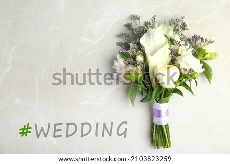 Bouquet of beautiful flowers and hashtag Wedding on light grey marble table, top view