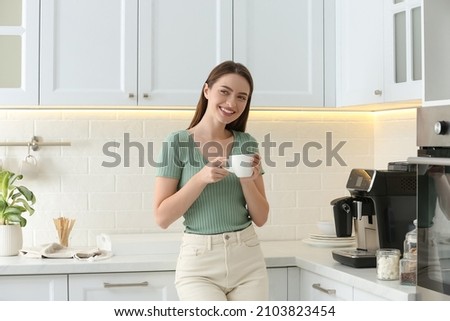 Young woman enjoying fresh aromatic coffee near modern machine in kitchen Royalty-Free Stock Photo #2103823454
