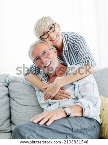 Portrait of a happy senior couple taking a selfie embracing hugging and having fun at home