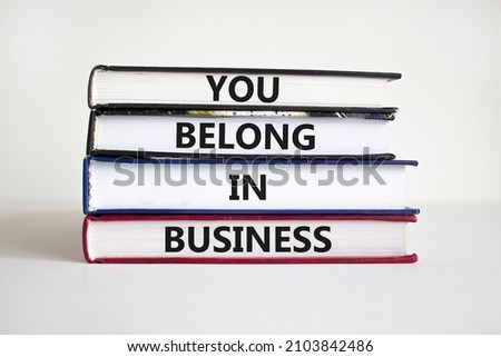 You belong in business symbol. Books with words 'You belong in business' on beautiful white background. Businessman hand. Business and you belong in business concept. Copy space.