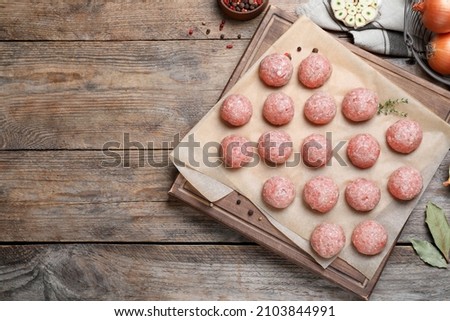 Many fresh raw meatballs on wooden table, flat lay Space for text