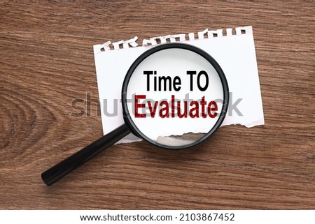 Time To Evaluate. text on magnifier glass on wood background