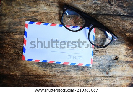 Envelope and glasses on wooden table.