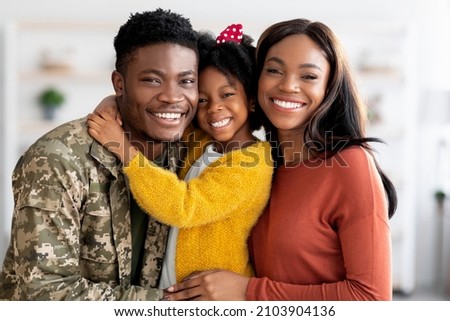 Portrait Of Happy Military Family, Black Soldier Father, Wife And Little Daughter Embracing Together At Home, Cheerful African American Man In Camouflage Uniform Hugging With Spouse And Female Child Royalty-Free Stock Photo #2103904136