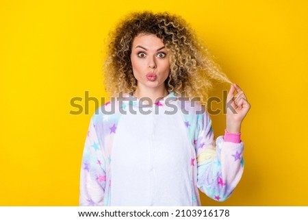 Portrait of attractive amazed funny girly wavy-haired girl pout lips touching hair isolated over bright yellow color background