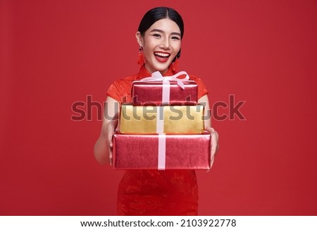 Happy Asian woman wearing traditional cheongsam qipao dress holding gift box isolated on red background. Happy Chinese new year