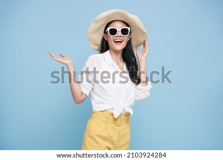 Young elegant beautiful Asian woman dressed in summer clothes smiling and pointing to empty copy space isolated on blue background.