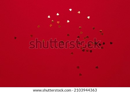Red background with golden sparkles in the shape of a heart. Beautiful abstract background for your design. Stylish confetti and glitter
