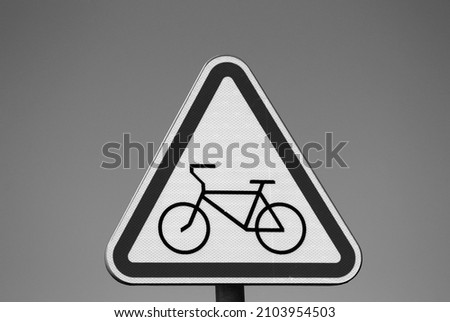 The road sign of the bicycle path is triangular in shape with the image of a bicycle against the sky.