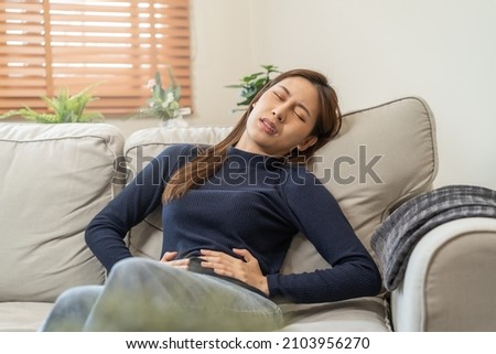 Flatulence asian young woman, girl hand in stomach ache, suffer from food poisoning, abdominal pain and colon problem, gastritis or diarrhoea. Patient belly, abdomen or inflammation, concept. Royalty-Free Stock Photo #2103956270
