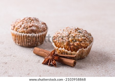 Homemade freshly baked pumpkin muffins with oatmeal and nuts on a beige textured background