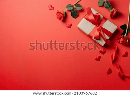 Red solid background with red hearts, gifts and confetti. The concept of Valentine Day.