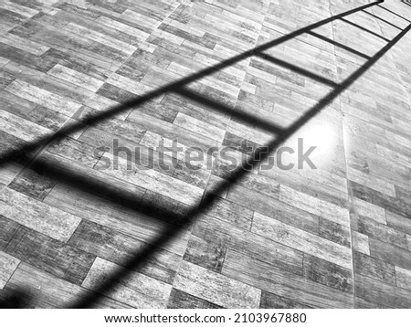 black and white picture of a shadow of a ladder creating leading lines diagonally