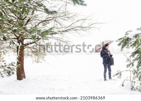 Defocus man in warm hat outside on rural winter snowy background holding umbrella. Happy millennial serious outdoor, cold weather. Snowy winter, lost in forest. Outside. Out of focus.