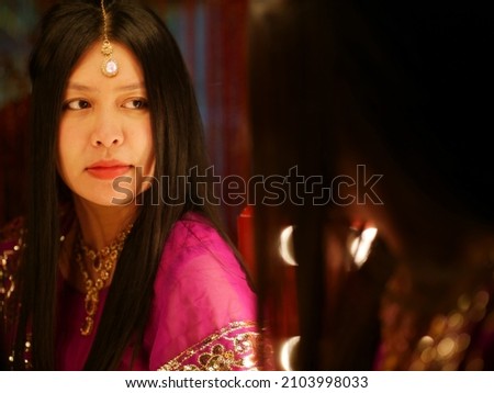 Asian woman wearing Indian dress looking at herself in the mirror to give her confidence.