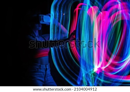 Metaverse digital Avatar, Metaverse Presence, digital technology, cyber world, virtual reality, futuristic lifestyle. Woman in VR glasses playing AR augmented reality NFT game with neon blur lines Royalty-Free Stock Photo #2104004912
