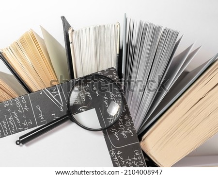 Magnifying lens over books with lot of pages. Concept of knowledge, education and studying.