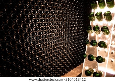 Bottles on racks in deep and long undergrounds caves, making champagne sparkling wine from chardonnay and pinor noir grapes in Reims, Champagne, France
