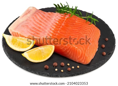 Red fish. Raw salmon fillet with rosemary, peppercorns and lemon on black round stone plate isolate on white background. Clipping path and full depth of field Royalty-Free Stock Photo #2104023353