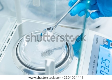 Close up scientist hands in rubber gloves use metal spatula for weighing white powder of the substance using digital balances. Preparation to clinical or pharmaceutical analysis Royalty-Free Stock Photo #2104024445