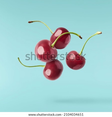 Fresh raw cheery falling in the air on turquoise background. Food zero gravity conception. High resolution image Royalty-Free Stock Photo #2104034651