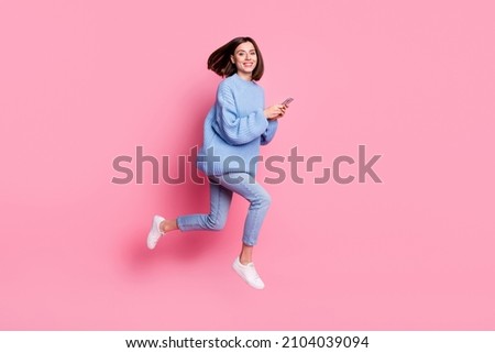 Full length body size view of attractive cheerful girl jumping using gadget blogging smm isolated over pink pastel color background