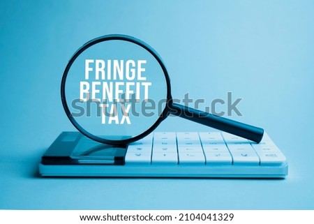 Finance and business concept. On a white background lies a calculator and a magnifying glass with the inscription - FRINGE BENEFIT TAX Royalty-Free Stock Photo #2104041329