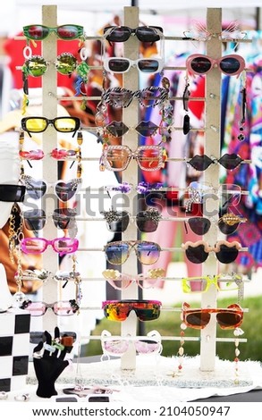 Row of sunglasses on display in a booth at a local arts and crafts fair in San Diego outside on a sunny day                              