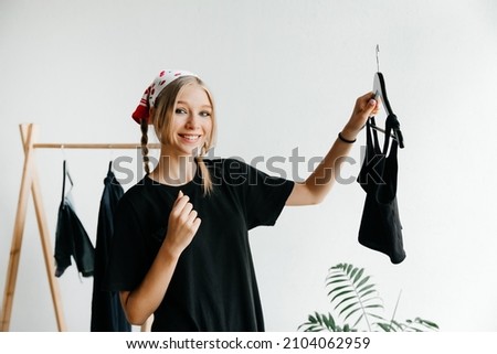 Image of young lady standing in front of a clothes rack indoors choosing dresses. Getting ready for going out