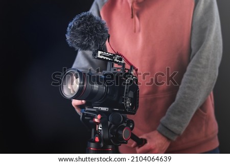 Filmmaker or cinematographer using professional camera gear to make documentaries and movies. Young cameraman, audiovisual, story telling and directing movies concepts.