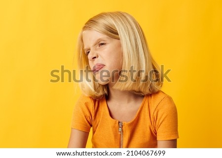 cute little girl with blond hair posing yellow background