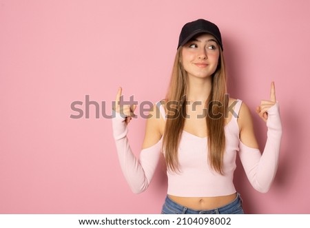 Young woman wearing sport clothing pointing fingers up isolated over pink background.