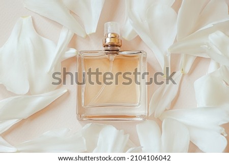 Perfume bottle and flower petals on pastel beige background. Natural cosmetics with aromatic oil. Design for advertising product. Copy space. Royalty-Free Stock Photo #2104106042