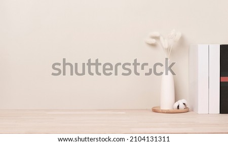 Home interior with decoration dried Bunny Tail grass, Front view, Beautiful Bunny Tail grass in vase and white book on wood table and beige cement wall background