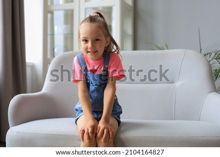 Excited child looking at camera while sitting in living room at home