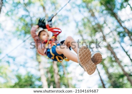 Boy descends the zip line while sitting on the safety belt