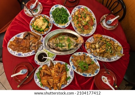 Flatlay of a full table spread containing traditional dishes for Chinese Lunar New Year. Each dish has a symbolic meaning for the celebration. Royalty-Free Stock Photo #2104177412