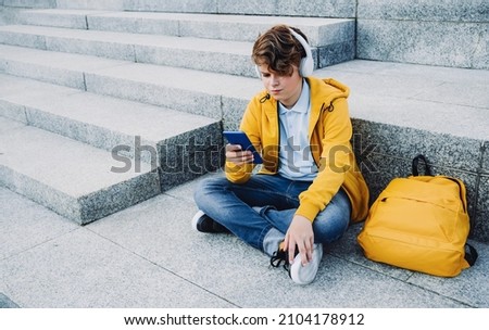 Child boy with headphones studying at home with laptop