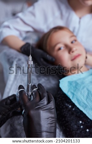 Little girl at dentist office, getting local anesthesia injection into gums. Cropped view of the dentist numbing gums for dental work. Pediatric dental care concept.