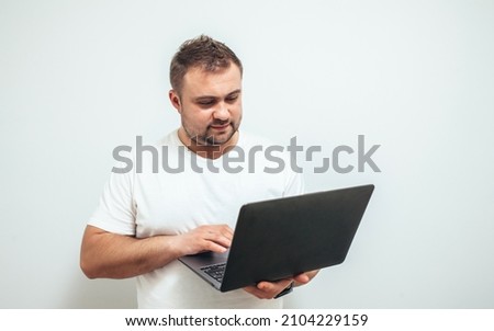 Focused handsome guy uses laptop for online work or communication on white studio background