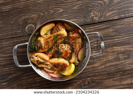 Chicken drumsticks baked with apples and herbs on wooden background with free text space. Top view, flat lay