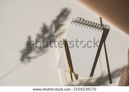 Aesthetic luxury workspace template. Spiral flip notebook with copy space in plant sunlight shadow on white background. Schedule, notes concept for blog, social media, web Royalty-Free Stock Photo #2104238570