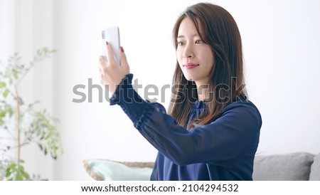 Young Asian woman using a smart phone in the room. facial recognition.