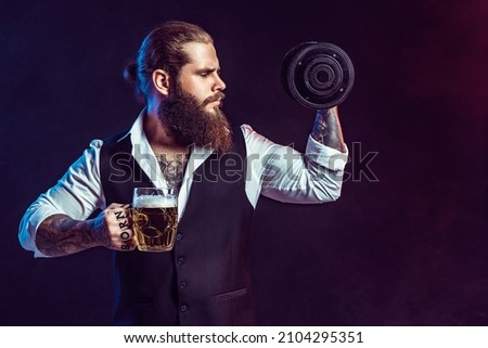 Beard man holds dumbbell and mug of beer in his hands on dark background. Concept of choice between alcohol and sport