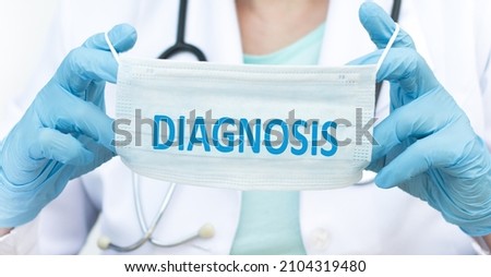 Diagnosis word on a protective mask in the hands of a doctor, medical concept