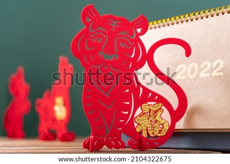 Chinese New Year of Tiger mascot paper cut and a 2022 calendar in front with Rat and Ox mascots at back, the Chinese means Happy New Year no logo no trademark Royalty-Free Stock Photo #2104322675